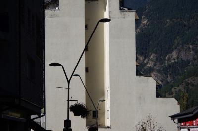 photograph “X.2021 — Pizza al teu gust” par David Farreny — www.farreny.net — Andorre, Andorra, La Massana, bâtiment, immeuble, building, béton, concrete, mur, wall, paroi, rue, street, lampadaires, lamps, métal, metal, pots, fleurs, flowers, plantes, plants, montagne, mountain, Pyrénées, Pyrenees, pizzeria, restaurant, Pizza al teu gust, Pizza à ton goût, Pizza to your liking, fenêtres, windows, arbres, trees