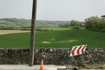 photograph “IV.2019 — Memories of Gascony” par David Farreny — www.farreny.net — France, Occitanie, Gascogne, Gers, Jegun, paysage, landscape, campagne, countryside, collines, hills, champ, field, bois, wood, route, road, muret, low wall, pierre, stone, poteau, post, pole, ciment, cement, cône, cone, circulation, traffic, signalisation, plastique, plastic, orange, panneau, sign, maisons, houses, horizon