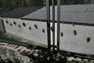 photograph “X.2023” par David Farreny — www.farreny.net — Andorre, Andorra, Canillo, clôture, fence, grillage, fencing, métal, metal, muret, low wall, pierre, stone, mur, wall, bâtiment, building, béton, concrete, toit, roof, tôle ondulée, corrugated iron, pots, fleurs, flowers, couleurs, colours, colors, ombre, shadow, rouge, red, violet, purple