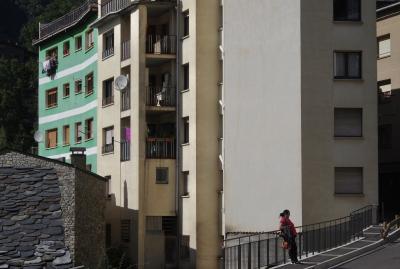 photograph “IX.2021” par David Farreny — www.farreny.net — Andorre, Andorra, Escaldes-Engordany, ville, city, rue, street, bâtiments, immeubles, buildings, béton, concrete, pierre, stone, ardoise, slate, fenêtres, windows, balcons, balconies, volets, shutters, stores, paraboles, satellite, dishes, linge, clothes, rambarde, guardrail, métal, metal, femme, woman, piétonne, pedestrian, gouttière, drainpipe, trottoir, pavement, bitume, blacktop, asphalt, asphalte, parpaings, breeze-blocks, sac, bag, façade, facade, vert, green, beige, profusion, laid, laideur, ugly, ugliness