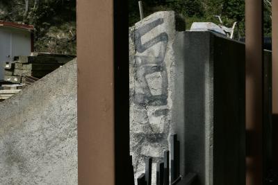 photograph “X.2023 — Whatever” par David Farreny — www.farreny.net — Andorre, Andorra, Encamp, mur, wall, ciment, cement, tag, graffiti, poteaux, posts, poles, métal, metal, gris, grey, gray, marron, brown, ombre, shadow, poutres, beams, bois, wood, bétonnière, mixer, arbres, trees