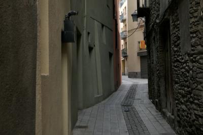 photograph “I.2022” par David Farreny — www.farreny.net — Espagne, España, Espanya, Spain, Catalogne, Cataluña, Catalunya, Lleida, Lérida, Alt Urgell, La Seu d'Urgell, ville, city, rue, street, ruelle, alley, bâtiments, immeubles, buildings, pierre, stone, béton, concrete, fenêtres, windows, balcons, balconies, drapeau, flag, lampe, lamp, tuyau, pipe, portes, doors, câbles, cables, fils, wires, métal, metal, hiver, winter