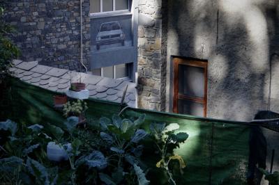 photograph “X.2021” par David Farreny — www.farreny.net — Andorre, Andorra, Escaldes-Engordany, immeubles, bâtiments, buildings, pierre, stone, béton, concrete, ville, city, toit, roof, ardoise, slate, jardin, garden, potager, vegetable, légumes, clôture, fence, bâche, tarpaulin, plastique, plastic, vert, green, fenêtre, window, coin, corner, angle, pots, ombre, shadow, voiture, car, peinture, painting, vitre, verre, glass, profusion