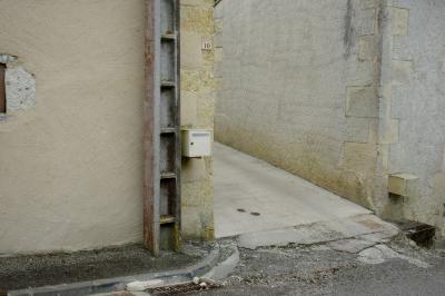 photograph “VI.2016” par David Farreny — www.farreny.net — France, village, rue, street, ruelle, allée, alley, maisons, houses, coin, corner, angle, pierre, stone, poteau, post, ciment, cement, crépi, roughcast, trottoir, pavement, bitume, blacktop, asphalte, asphalt, boîte à lettres, mailbox, postbox, plaque, plate, numéro, number, nombre, 10, béton, concrete, Occitanie, Gascogne, Gers, Jegun