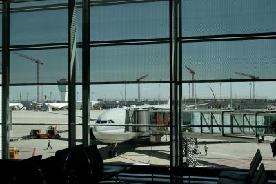 photograph “VIII.2012” par David Farreny — www.farreny.net — Allemagne, Germany, Deutschland, Bavière, Bavaria, Bayern, Munich, München, aéroport, airport, aérogare, air terminal, verrière, baie, window, verre, vitre, glass, avion, plane, piliers, pillars, colonnes, columns, structure, métal, metal, pistes, runways, grues, cranes, chantier, building site, hommes, men, personnel, chaises, chairs, escaliers, stairs, passerelle, embarquement, boarding, bridge, véhicules, vehicles, ciel, sky, M