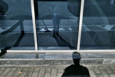 photograph “X.2023 — Ax it” par David Farreny — www.farreny.net — Andorre, Andorra, Canillo, rue, street, trottoir, pavement, pierre, stone, vitrine, baie, bay, window, vitre, glass, verre, reflet, reflection, bleu, blue, bitume, blacktop, asphalte, asphalt, ombre, shadow, homme, man, appareil photo, camera, inscription, signalisation, sign, taxi, parking, space, place, bâtiments, immeubles, buildings, autoportrait, selfportrait, poussière, dust