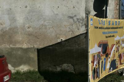 photograph “XII.2023 — Whatever” par David Farreny — www.farreny.net — France, Occitanie, Tarn-et-Garonne, Caussade, mur, wall, maison, house, ciment, cement, pierre, stone, panneau, sign, routier, roadsign, marché, market, annonce, announcement, voiture, car, métal, metal, rouge, red, illustration, information, municipale, municipal, tags, graffitis, clôture, fence, grille, railing, ombre, shadow