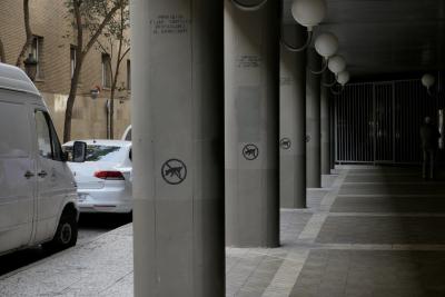 photograph “III.2023” par David Farreny — www.farreny.net — Espagne, España, Spain, Aragon, Aragón, Saragosse, Zaragoza, Caesaraugusta, ville, city, rue, street, voitures, cars, arbres, trees, bâtiment, immeuble, building, béton, concrete, piliers, pillars, colonnes, columns, fenêtres, windows, lampes, lamps, grille, fence, métal, metal, rétroviseur, mirror, miroir, tronc, trunks, feuillage, foliage, trottoir, pavement, inscription, message, prohibido fijar carteles, interdiction de coller des affiches, forbidden to stick posters, responsable el anunciante, l'annonceur est responsable, the advertiser is responsible, passing, passer-by, piéton, pedestrian, homme, man, brique, brick, logo, symbole, symbol, chien, dog, interdit, forbidden
