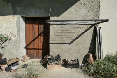 photograph “VIII.2024” par David Farreny — www.farreny.net — France, Occitanie, Gascogne, Gascony, Gers, Biran, maison, house, porte, door, bois, wood, mur, wall, ciment, cement, étendoir, clothes rack, ombre, shadow, été, summer, lignes, lines, parallèles, parallel, cageots, crates, brique, brick, pots, herbe, grass, tuiles, tiles, dépression, depression