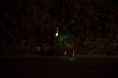 photograph “VII.2023 — At night” par David Farreny — www.farreny.net — Andorre, Andorra, Canillo, nuit, night, route, road, bitume, blacktop, asphalte, asphalt, feu rouge, red light, vert, green, cône, cone, plastique, plastic, orange, coffre, box, batterie, battery, métal, metal, ligne, line, peinture, paint, blanche, white, paroi, wall, colline, hill, végétation, vegetation, rochers, rocks