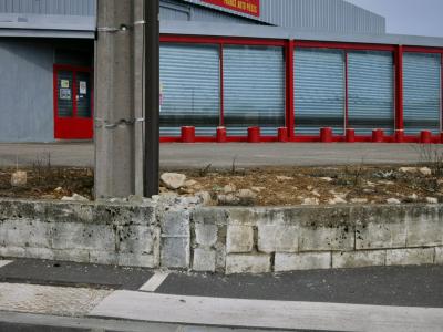 photograph “III.2012 — France pièces” par David Farreny — www.farreny.net — France, magasin, store, métal, metal, tôle ondulée, corrugated iron, volets, shutters, trottoir, pavement, béton, concrete, pylône, pylon, ciment, cement, enseigne, sign, porte, door, Occitanie, Aveyron, Rouergue, Sébazac-Concourès, Rodez
