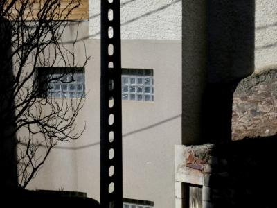 photograph “II.2014” par David Farreny — www.farreny.net — France, poteau, post, pole, électrique, electricity, câbles, cables, fils, wires, ombre, shadow, bâtiment, immeuble, building, mur, wall, fenêtres, windows, verre, glass, pierre, stone, béton, concrete, arbre, tree, branches, trous, holes, porte, door, bois, wood, pylône, coin, corner, angle, profusion, Occitanie, Aveyron, Rouergue, Rodez