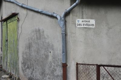 photograph “II.2015” par David Farreny — www.farreny.net — France, Occitanie, Aveyron, Rouergue, Moyrazès, hangar, shed, vieux, old, ciment, cement, portail, gate, bois, wood, vert, green, gouttières, drainpipes, métal, metal, plaque, plate, rue, street, avenue des Évêques, avenue of the Bishops, mur, wall, chaîne, chain, pierre, stone, rouille, rust, rusty, grillage, fencing