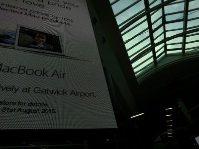 photograph “VIII.2015” par David Farreny — www.farreny.net — Royaume-Uni, United Kingdom, Angleterre, England, GB, UK, Londres, London, West Sussex, Crawley, Gatwick, aéroport, airport, aérogare, terminal, hall, publicité, advertising, pub, ad, écran, screen, électronique, electronic, pixels, Apple, MacBook Air, ordinateurs, portables, laptops, computers, Mac, promotion, prix, prices, baie, window, ciel, sky, soir, evening, lumières, lights