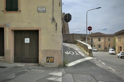 photograph “VIII.2022 — Via Dante Aligheri” par David Farreny — www.farreny.net — Italie, Italia, Italy, Toscane, Toscana, Tuscany, Sienne, Siena, San Quirico d'Orcia, rue, street, Dante Aligheri, panneau, sign, plaque, porte, door, fenêtres, windows, carrefour, croisement, crossing, bitume, blacktop, asphalte, asphalt, coin, corner, angle, stop, arrêt, lampadaire, lamp, voitures, cars, fils, wires, câbles, cables, volets, shutters, bois, wood, 1A, 712, mur, wall, pierre, stone, maisons, houses, ciel, sky