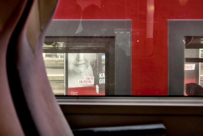 photograph “IV.2024” par David Farreny — www.farreny.net — France, Occitanie, Haute-Garonne, Toulouse, Matabiau, gare, station, train, siège, seat, fenêtre, window, verre, vitre, glass, perspective, publicité, advertising, pub, ad, livre, book, roman, novel, femme, woman, auteur, author, Enfin en poche !, Harper Collins, voie ferrée, railway, reflet, reflection, photographe, photographer