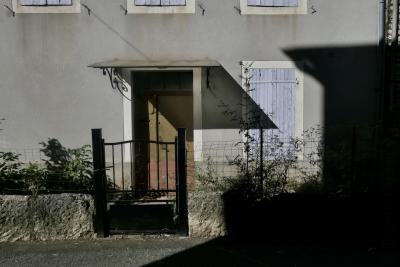 photograph “IX.2024 — Faces of home, 209” par David Farreny — www.farreny.net — France, Occitanie, Tarn-et-Garonne, Septfonds, maison, house, façade, facade, porte, door, bois, wood, volets, shutters, fenêtres, windows, portail, gate, métal, metal, clôture, fence, grillage, fencing, muret, low wall, pierre, stone, ciment, cement, crépi, roughcast, auvent, awning, ombre, shadow, rue, street, bitume, blacktop, asphalte, asphalt, domicile, home