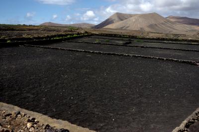photograph “V.2016 — Lancerotte, 56” par David Farreny — www.farreny.net — Espagne, España, Spain, Canaries, Canarias, Canary, Lanzarote, Lancerotte, île, island, volcan, volcano, cratère, crater, montagne, mountain, paysage, landscape, champ, field, lave, lava, cailloux, stones, rectangles, nuages, clouds, noir, black, El Morro de Uga