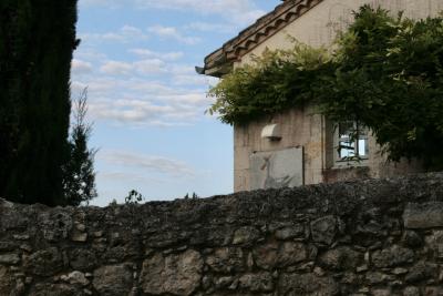 photograph “VIII.2012 — Faces of home, 68” par David Farreny — www.farreny.net — France, Occitanie, Gers, Lomagne, Gascogne, Gascony, Plieux, maison, house, mur, wall, pierre, stone, cyprès, cypress, fenêtre, window, nuages, clouds, mosaïque, mosaic, oie, goose, couronne, crown, toit, roof, génoise, eaves, tuiles, tiles, gouttière, gutter, domicile, home, voisine, neighbour, neighbor, chien, dog, nuisance, aboiements, barking