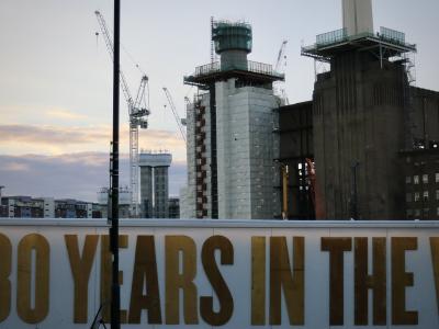 photograph “VIII.2015 — Years” par David Farreny — www.farreny.net — Royaume-Uni, United Kingdom, Angleterre, England, GB, UK, Londres, London, Battersea, Wandsworth, centrale électrique, power station, Battersea power station, cheminées, chimneys, brique, brick, usine, factory, industrie, industry, ville, city, lampadaire, réverbère, street lamp, publicité, advertising, pub, ad, chantier, works, rénovation, renovation, grues, cranes, métal, metal, lettres, letters, caractères, characters, years in the, échafaudages, scaffolding, plateformes, platforms, immeubles, buildings, bâtiments, soir, evening, bois, wood, ciel, sky, nuages, clouds, lumières, lights