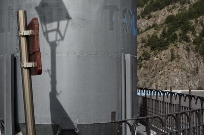 photograph “V.2023” par David Farreny — www.farreny.net — Andorre, Andorra, Canillo, montagne, mountain, Pyrénées, Pyrenees, silo, métal, metal, rambarde, guardrail, panneau, sign, poteau, post, pole, bois, wood, lampadaire, lamp, ombre, shadow, inscription, marque, brand, Tol, rocher, rock, arbres, trees, paroi, wall, plateforme, platform, parking, car park, bitume, blacktop, asphalte, asphalt