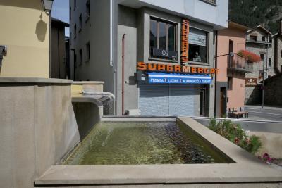 photograph “IX.2022” par David Farreny — www.farreny.net — Andorre, Andorra, Canillo, ville, city, immeuble, bâtiment, building, supermarché, supermarket, supermercat, Superpas, béton, concrete, enseigne, sign, fenêtres, windows, fontaine, fountain, eau, water, fleurs, flowers, lampe, lamp, balcon, balcony, ombre, shadow, gouttière, gutter, métal, metal, rue, street, pierre, stone, montagne, mountain