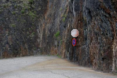 photograph “VII.2023” par David Farreny — www.farreny.net — Andorre, Andorra, Canillo, route, road, bitume, blacktop, asphalte, asphalt, virage, turn, mur, wall, rocher, rock, humide, wet, panneaux, signs, routiers, roadsigns, stop, métal, metal, montagne, mountain, traces, tracks