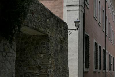 photograph “VIII.2022” par David Farreny — www.farreny.net — Italie, Italia, Italy, Toscane, Toscana, Tuscany, Sienne, Siena, San Quirico d'Orcia, bâtiment, building, pierre, stone, lampe, lamp, angle, coin, corner, façade, facade, fenêtres, windows, grilles, railings