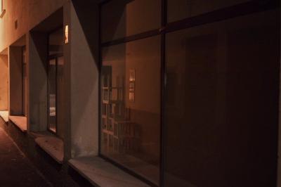 photograph “VII.2023 — At night” par David Farreny — www.farreny.net — Andorre, Andorra, Encamp, ruelle, alley, rue, street, bâtiment, building, immeuble, magasin, shop, store, vitrine, windows, fenêtres, baies, bay, verre, vitre, glass, béton, concrete, empty, vide, meubles, furniture, tables, empilées, stacked, cadres, frames, pénombre, darkness, sombre, dark, nuit, night, lumière, light, bitume, blacktop, asphalte, asphalt