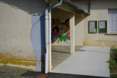 photograph “X.2020” par David Farreny — www.farreny.net — France, école, school, préau, couvert, covered, courtyard, mur, wall, ciment, cement, gouttière, drainpipe, gutter, métal, metal, béton, concrete, panneaux, boards, fenêtre, window, volets, shutters, herbe, grass, peintures, paintings, fresques, frescoes, enfants, children, éléphant, elephant, bitume, blacktop, asphalte, asphalt, poteau, pilier, pillar, grille, railings, Occitanie, Gascogne, Gers, Roquefort