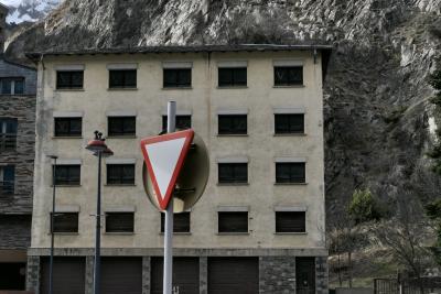 photograph “III.2022” par David Farreny — www.farreny.net — Andorre, Andorra, Canillo, hiver, winter, immeuble, bâtiment, building, béton, concrete, pierre, stone, montagne, mountain, rocher, rock, neige, snow, lampadaire, lamp, street lamp, fenêtres, windows, panneau, routier, sign, roadsign, garages, portails, gates, arbre, tree, métal, metal