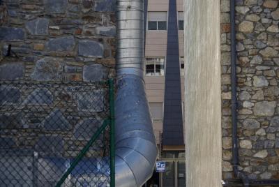 photograph “II.2023 — Faces of home, 166” par David Farreny — www.farreny.net — Andorre, Andorra, Canillo, immeubles, bâtiments, buildings, passages, tuyau, pipe, métal, metal, murs, walls, pierre, stone, béton, concrete, grillage, fencing, gouttière, drainpipe, fenêtres, windows, porte, door, volets, shutters, vitre, verre, glass, façade, facade, panneau, sign, parking, inscription, magatzem, reflet, reflection, crottes, oiseaux, bird, droppings, domicile, home