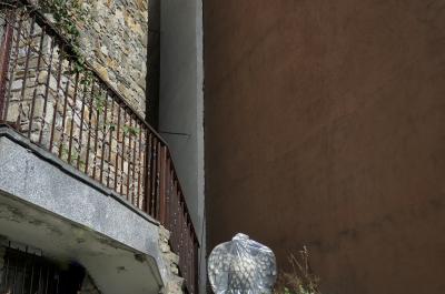 photograph “XI.2022” par David Farreny — www.farreny.net — Andorre, Andorra, Canillo, maison, house, pierre, stone, terrasse, terrace, rambarde, railings, métal, metal, mur, wall, béton, concrete, statue, oiseau, bird, aigle, eagle, plastique, plastic, bâche, tarpaulin, emballage, wrapping, sculpture