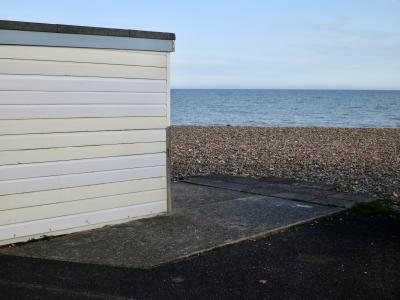 photograph “V.2013” par David Farreny — www.farreny.net — Royaume-Uni, United Kingdom, Grande-Bretagne, Great Britain, Angleterre, England, GB, UK, Sussex, West Sussex, Worthing, front de mer, seafront, plage, beach, galets, pebbles, shingle, mer, sea, Manche, Channel, horizon, eau, water, paysage, landscape, marin, seascape, soir, evening, cabine, bain, bathing, hut, bois, wood, planches, planks, ciment, cement, bitume, blacktop, asphalte, asphalt