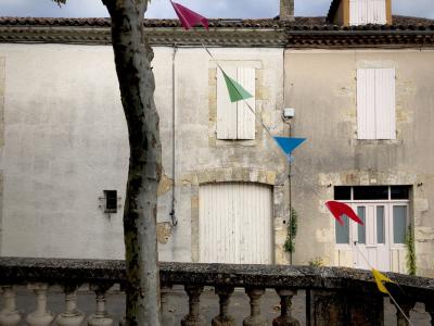 photograph “VIII.2018” par David Farreny — www.farreny.net — France, Occitanie, Gascogne, Gascony, Gers, Jegun, maison, house, arbre, tree, platane, plane tree, tronc, trunk, porte, door, portail, gate, fenêtres, windows, volets, shutters, bois, wood, génoises, pierre, stone, cheminée, chimney, balustrade, balustre, baluster, guirlande, fanions, pennant, garland, fête, village, party, couleurs, colours, colors