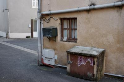 photograph “III.2014 — Faces of home, 79” par David Farreny — www.farreny.net — France, domicile, home, ville, city, rue, street, maison, house, fenêtre, window, grille, barreaux, bars, tuyaux, pipes, gouttière, drainpipe, gutter, boîte aux lettres, letterbox, mailbox, ciment, cement, métal, metal, porte, door, volets, shutters, câbles, cables, coin, corner, angle, bitume, blacktop, asphalte, asphalt, plastique, plastic, crépi, roughcast, profusion, Occitanie, Aveyron, Rouergue, Rignac