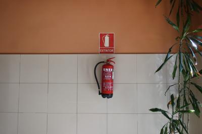photograph “IV.2024 — UNIXtintor” par David Farreny — www.farreny.net — Andorre, Andorra, Canillo, mur, wall, carrelage, tiling, extincteur, extinguisher, incendie, fire, UNIX, rouge, red, panneau, sign, extintor, tuyau, pipe, poignée, handle, métal, metal, plante, plant, feuilles, leaves, foliage, feuillage