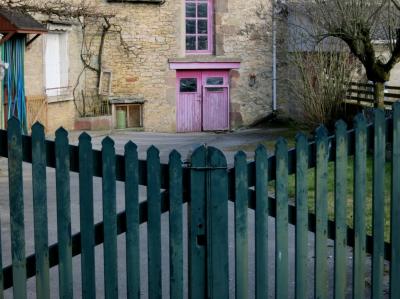 photograph “II.2012 — Faces of home, 57” par David Farreny — www.farreny.net — France, domicile, home, cour, yard, courtyard, portail, gate, remise, shed, porte, door, rose, pink, vert, green, bois, wood, rideau, curtain, entrée, entry, entrance, arbre, tree, herbe, grass, gazon, lawn, maison, house, gouttière, drainpipe, fenêtres, windows, volets, shutters, gaz, gas, bouteille, cylinder, pierre, stone, clôture, fence, Occitanie, Aveyron, Rouergue, Agen-d'Aveyron