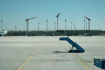 photograph “VIII.2012” par David Farreny — www.farreny.net — Allemagne, Germany, Deutschland, Bavière, Bavaria, Bayern, Munich, München, aéroport, airport, béton, concrete, métal, metal, pistes, runways, grues, cranes, chantier, building site, M, passerelle, embarquement, boarding, bridge, projecteurs, floodlights, lignes, jaunes, yellow, lines, vide, empty, emptiness