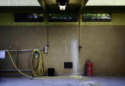 photograph “IV.2006 — This deadly boredom” par David Farreny — www.farreny.net — France, Occitanie, Aveyron, Rouergue, Rodez, garage, lieu de travail, workplace, dimanche, Sunday, tuyau, arrosage, garden, host, barrière, guardrail, métal, metal, pompe, dump, brosse, brush, carrelage, tile, mur, wall, sol, floor, seau, bucket, tuyaux, pipes, néon, neon, lumière, light, lucarne, skylight, béton, concrete, trace, peinture, paint