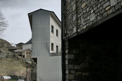 photograph “III.2022 — Faces of home, 139. ↑” par David Farreny — www.farreny.net — Andorre, Andorra, Canillo, bâtiments, immeubles, buildings, maisons, houses, pierre, stone, béton, concrete, métal, metal, tôle ondulée, corrugated iron, lampadaires, street lamps, gouttière, drainpipe, fenêtres, windows, toit, roof, voiture, car, jardin, garden, branches, arbre, tree, hiver, winter, domicile, home, flèche, arrow