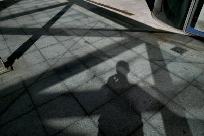 photograph “X.2023” par David Farreny — www.farreny.net — Andorre, Andorra, Canillo, sol, floor, ground, dallage, paving, ombres, shadows, homme, man, photographe, photographer, métal, metal, verre, vitre, glass, croisements, crossings, autoportrait, selfportrait