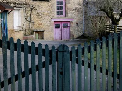 photograph “II.2012 — Faces of home, 57” par David Farreny — www.farreny.net — France, domicile, home, cour, yard, courtyard, portail, gate, remise, shed, porte, door, rose, pink, vert, green, bois, wood, rideau, curtain, entrée, entry, entrance, arbre, tree, herbe, grass, gazon, lawn, maison, house, gouttière, drainpipe, fenêtres, windows, volets, shutters, gaz, gas, bouteille, cylinder, pierre, stone, clôture, fence, Occitanie, Aveyron, Rouergue, Agen-d'Aveyron