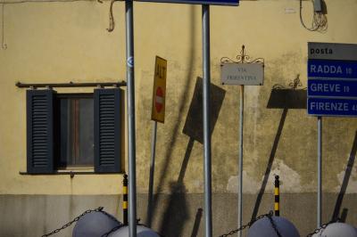 photograph “X.2019” par David Farreny — www.farreny.net — Italie, Italia, Italy, Toscane, Toscana, Tuscany, Sienne, Siena, Chianti, Castellina in Chianti, carrefour, crossroads, panneaux, routiers, signs, roadsigns, automne, autumn, fall, soir, evening, ombres, shadows, maison, house, mur, wall, fenêtre, window, volets, shutters, persiennes, louver, bois, wood, métal, metal, sens interdit, one way, ALT, Via Fiorentina, posta, Radda, Greve, Firenze, Florence, sphères, spheres, poteaux, posts, bollards, chaînes, chains, fils, électriques, electricity, wires, cables, câbles, Schilderwald