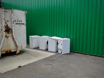 photograph “VI.2014” par David Farreny — www.farreny.net — France, benne, skip, métal, metal, lave-linge, machines à laver, washing machines, rebut, scrap, déchetterie, waste collection centre, paroi, wall, tôle ondulée, corrugated iron, vert, green, bitume, blacktop, asphalte, asphalt, 0168, tuyau, tubing, déchets, waste, rouille, rust, rusty, inscription, sign, Occitanie, Rouergue, Aveyron, Sébazac-Concourès