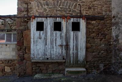 photograph “II.2014” par David Farreny — www.farreny.net — France, garage, façade, facade, portail, gate, porte, door, bois, wood, pierre, stone, parpaings, breeze-blocks, ouvertures, openings, peinture, écaillée, chipped, flaking, paint, métal, metal, rouille, rust, rusty, arche, arc, arch, marche, step, ciment, cement, Occitanie, Aveyron, Rouergue, Cassagnes-Bégonhès