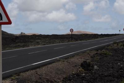 photograph “V.2016 — Lancerotte, 17” par David Farreny — www.farreny.net — Espagne, Spain, España, Canaries, Canary, Canarias, Lanzarote, Lancerotte, île, island, Taús, route, road, bitume, blacktop, asphalte, asphalt, panneaux, routiers, roadsigns, lave, lava, montagnes, mountains, volcans, volcanoes, nuages, clouds, paysage, landscape, rochers, rocks, rocs, bord, edge, Masdache