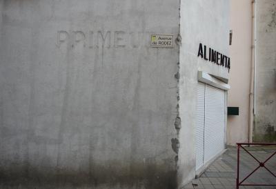 photograph “II.2014” par David Farreny — www.farreny.net — France, mur, wall, ciment, cement, enseigne, sign, magasin, shop, épicerie, alimentation, grocery, grocer's, store, food, primeur, fruits et légumes, early fruit and vegetables, greengrocer, plaque, rue, street, plate, coin, angle, corner, barrière, guardrail, métal, metal, blind, gouttière, drainpipe, boîte à lettres, letterbox, mailbox, pavement, tiling, ville, city, traces, marks, fermé, closed, Occitanie, Rouergue, Aveyron, Réquista, avenue de Rodez