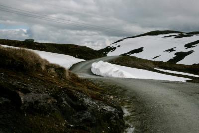 photograph “VII.2012 — Run away to the North, 31” par David Farreny — www.farreny.net — Norvège, Norway, Norge, Sogn og Fjordane, Hordaland, Skjelingen, montagne, mountain, route, road, neige, snow, rocher, rock, roc, nuages, clouds, paysage, landscape, herbe, grass, fils, wires, câbles, cables, virage, bend, asphalte, asphalt, bitume, blacktop