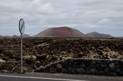 photograph “V.2016 — Lancerotte, 36” par David Farreny — www.farreny.net — Espagne, España, Canaries, Canarias, Canary, Spain, Lanzarote, Lancerotte, île, island, montagne, mountain, volcan, volcano, Caldera colorada, rouge, red, lave, lava, route, road, panneau, sign, muret, low wall, bitume, blacktop, asphalte, asphalt, paysage, landscape, pierre, stone, métal, metal, Masdache